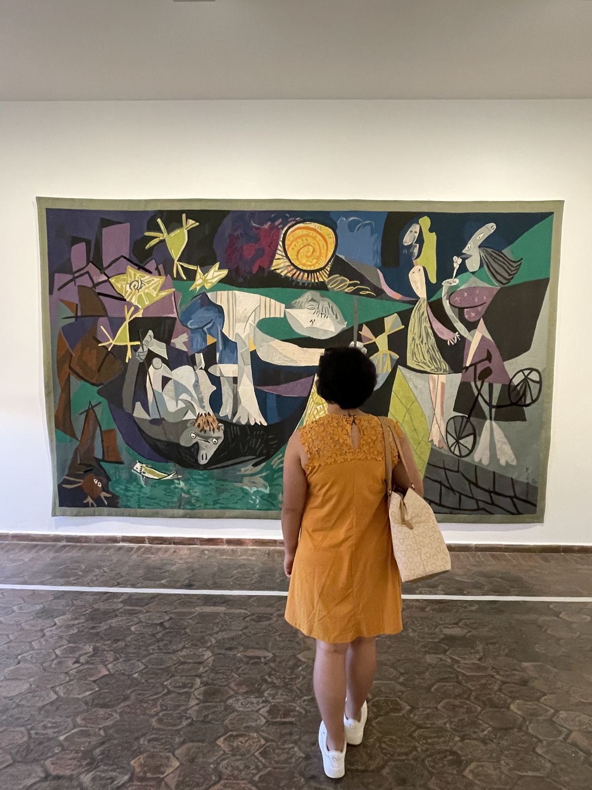 Sucheta from behind, standing in front of a large Picasso tapestry at the Picasso Museum in Antibes